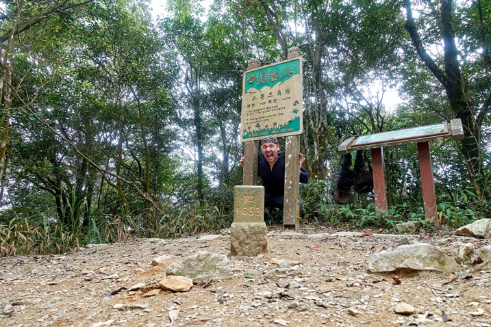 尾寮山健行 - 男子在三角點石頭旁擺姿勢