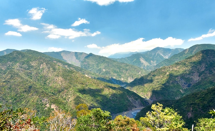 Mountain landscape with riverbed below - blue sky and white clouds