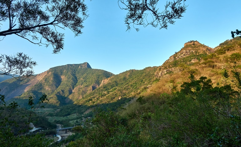 Mountains and farms below - bridge and small river - blue sky