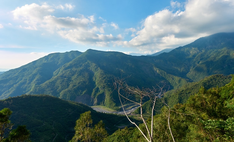 Mountain landscape - riverbed below - blue sky and white clouds